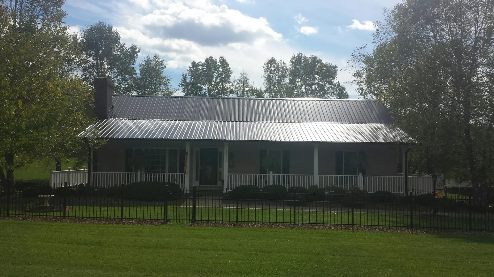 Gray metal roof on a brick ranch with a full width front porch — Gutter Guard Installation work by our crew in Cuba