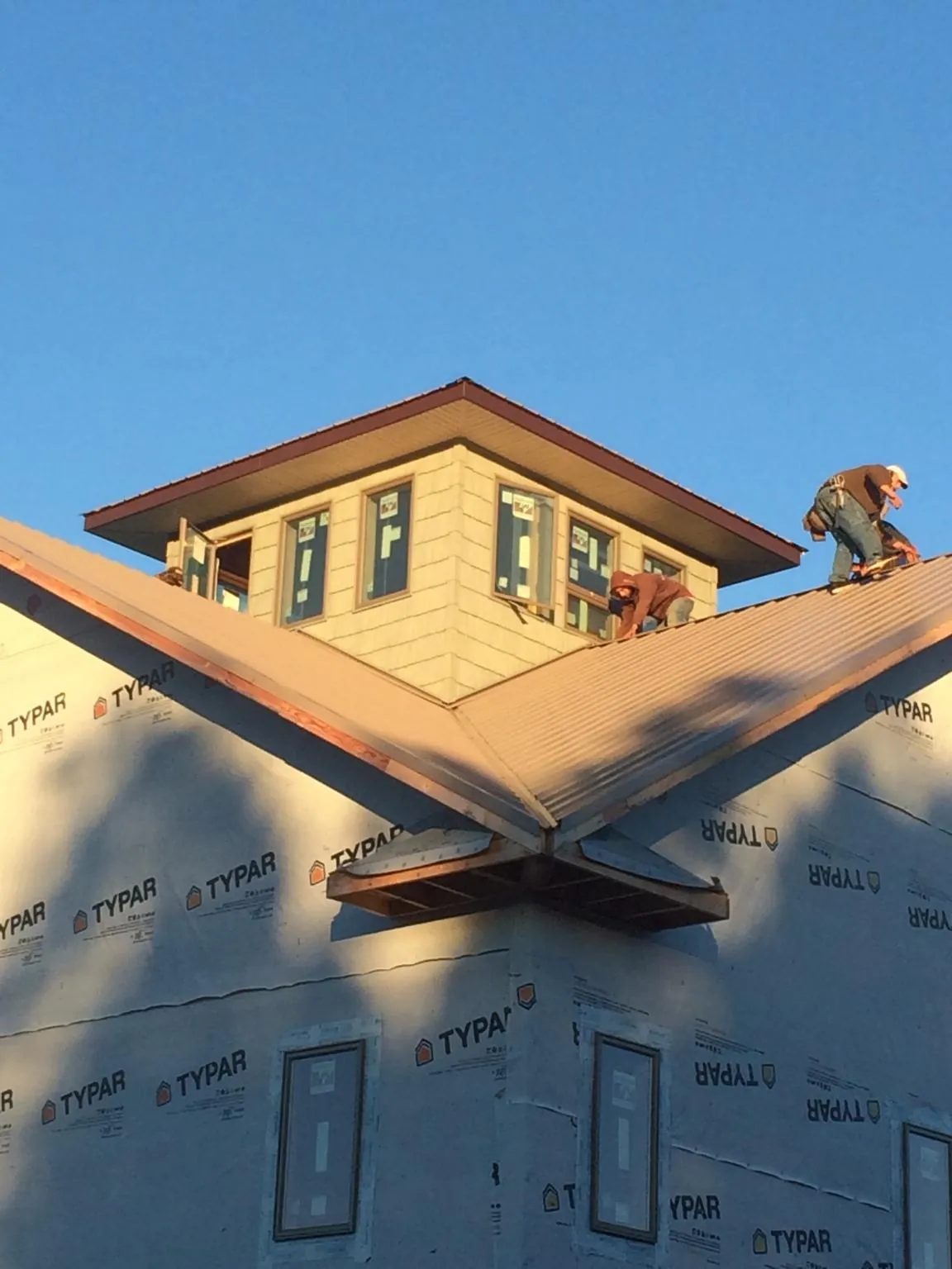 Roofers working around a rooftop cupola on a new metal roof at sunset — Roof Waterproofing in Cuba by Roofing Brothers